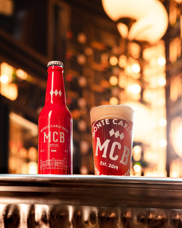 Verre de bière ambrée Monte Carlo Beer posé sur une table en bois