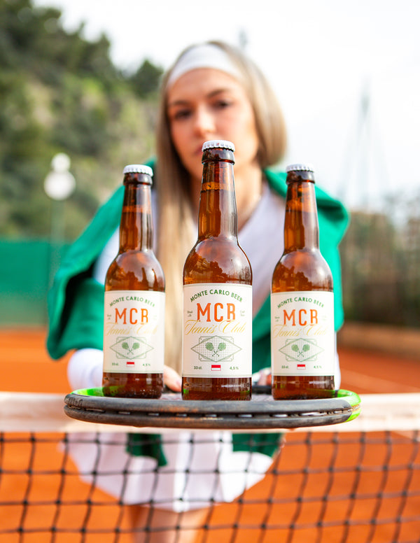 Trois bières blonde spécial "tennis club" de Monte Carlo Beer, posée sur une raquette de Tennis et tenu par une joueuse de tennis