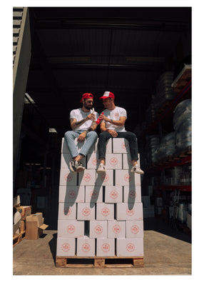William et Anthony, assis sur une palette de carton Monte Carlo Beer