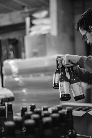 Un homme en train de préparer les bières Monte Carlo Beer dans un carton