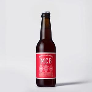 Bouteille de MCB Ambrée, étiquette rouge sur fond blanc.